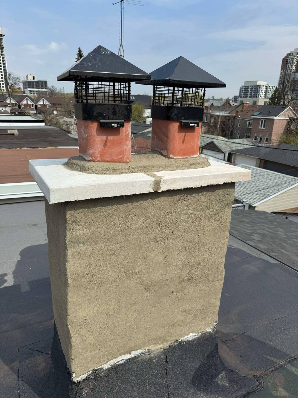 Freshly parged chimney with twin capped flues, west Toronto