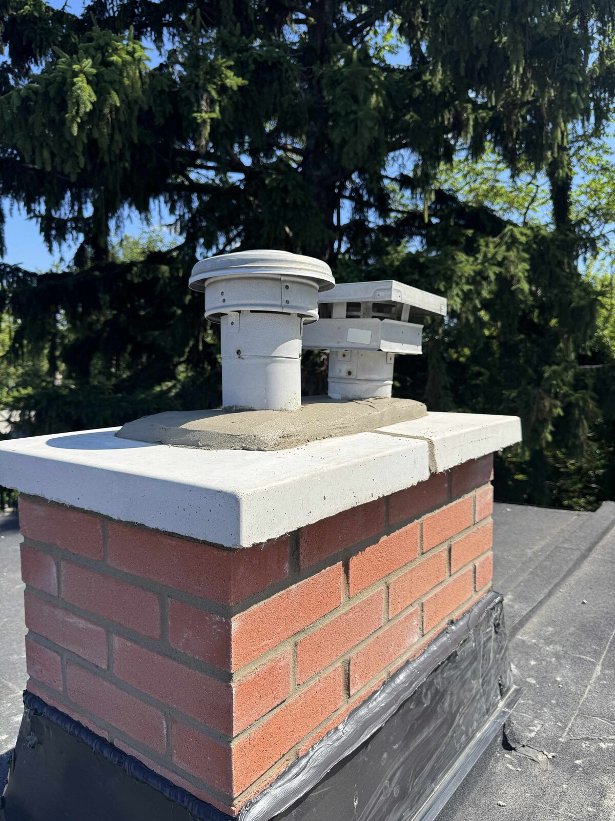 Rebuilt red-brick chimney with new concrete crown and twin caps
