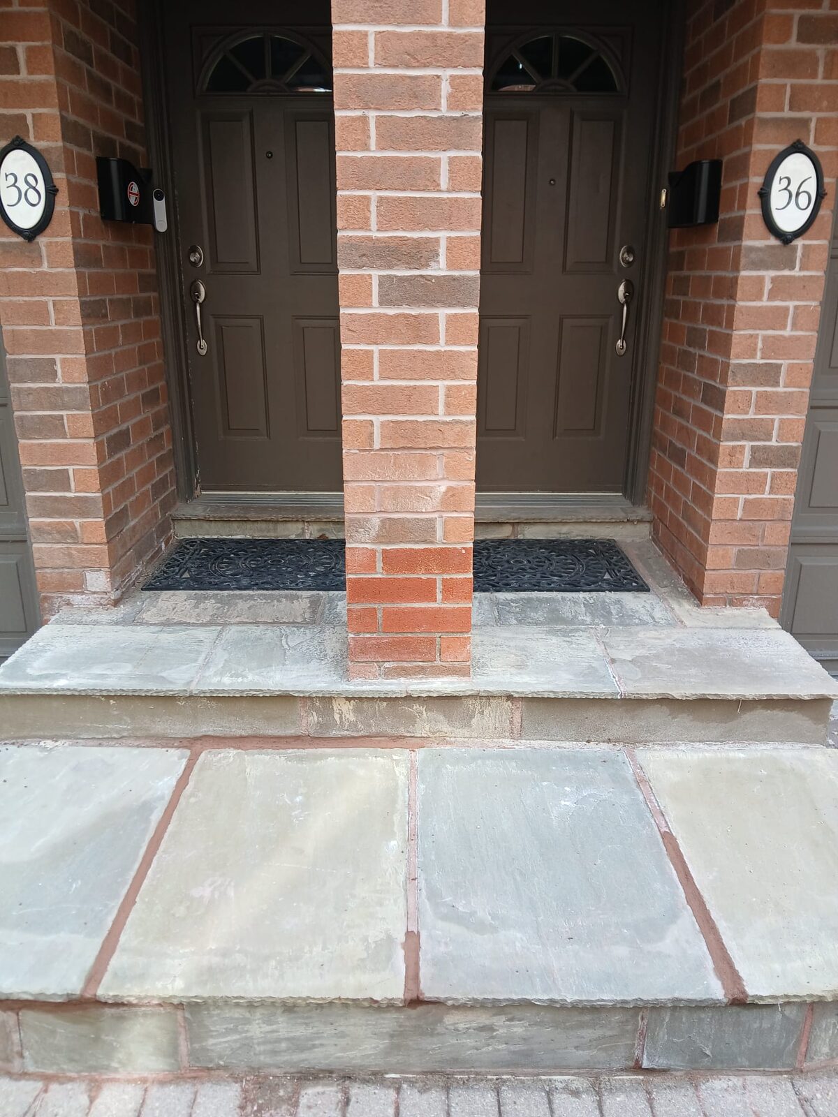 Rebuilt brick porch columns and stone steps at a twin entry