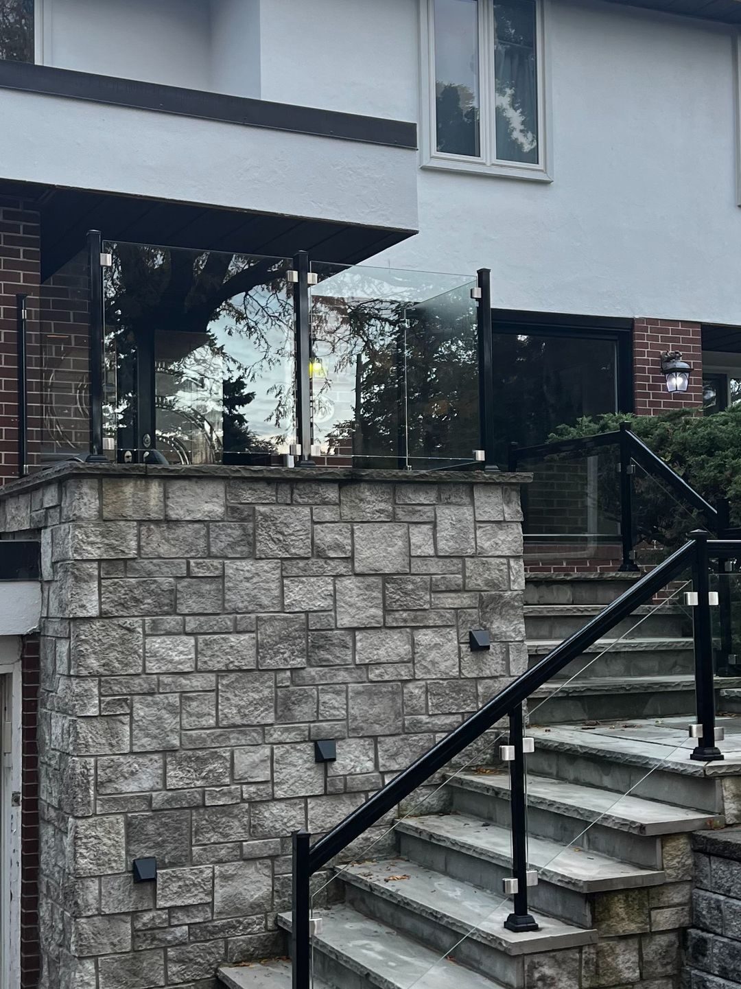 Squared-stone porch with flagstone steps and glass railings